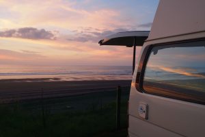 a campervan with the back door open at sunset